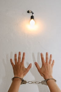 Low angle view of hand against illuminated wall