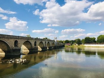 Arch bridge over river against sky