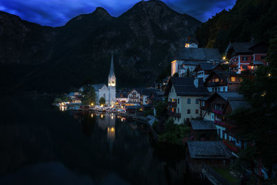 Illuminated buildings in town against sky at night