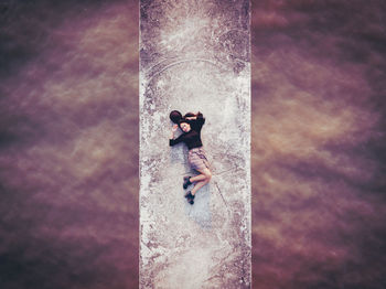 Aerial view of woman lying on bridge over sea