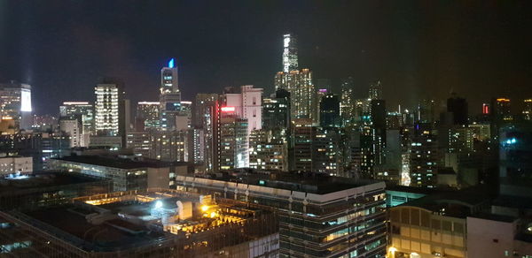 Illuminated modern buildings in city against sky at night