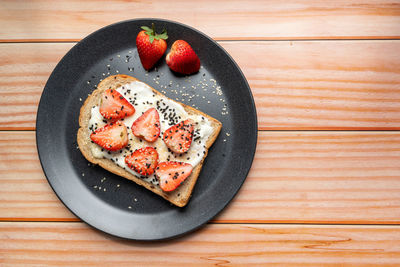 Healthy breakfast toasts with strawberry, yoghurt with whole grain sandwich bread on black dish