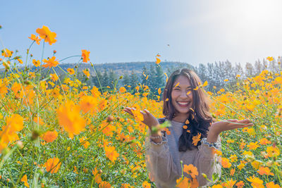 Portrait of woman standing by yellow flowering plants