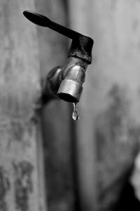 Close-up of water drops on faucet against wall