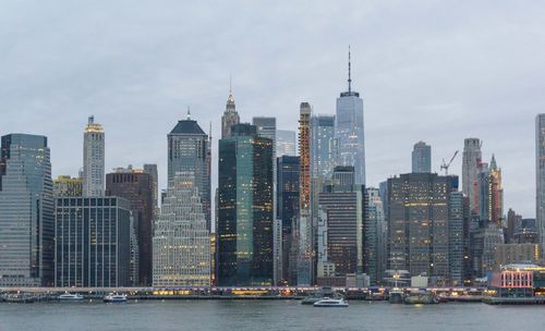 River with modern buildings in background against sky