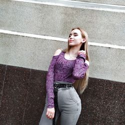 Portrait of a beautiful young woman standing against wall