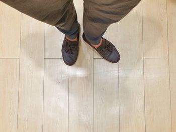 Low section of man standing on hardwood floor