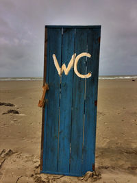 View of wooden post on beach against sky