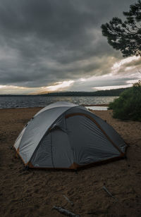 Tent on beach against sky during sunset