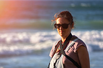 Young woman wearing sunglasses standing at beach