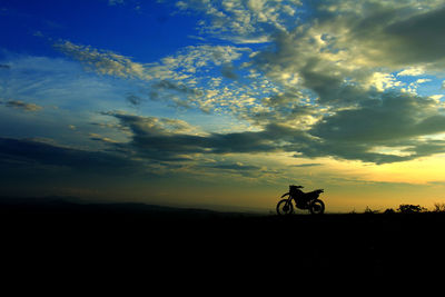 Silhouette man riding bicycle against sky during sunset