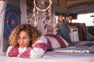 Rear view of woman sitting on bed at home