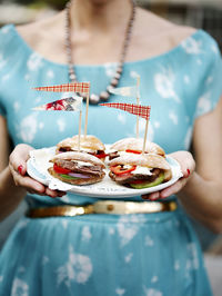 Woman holding plate with sandwiches