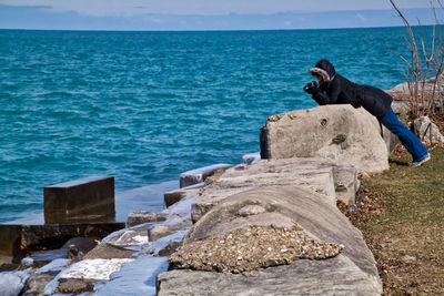 Side view of person leaning on rock at lake michigan