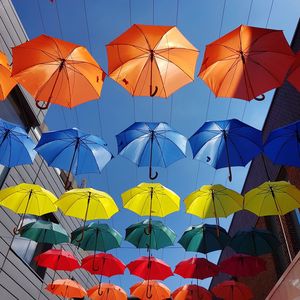 Low angle view of colorful umbrellas hanging against clear sky