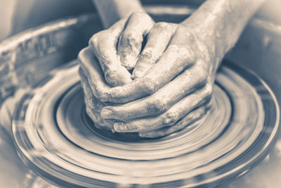 Old vintage photo. master potter folded together hands sculpts clay product on potter's wheel. hand 