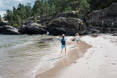 Brother and sister racing along the sand together at the beach