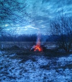 Bonfire in field against cloudy sky
