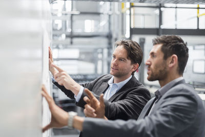 Two businessmen discussing plan in modern factory