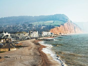 Scenic view of sea by buildings against sky