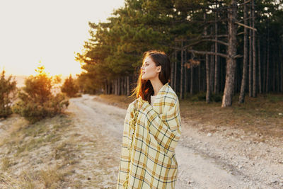 Full length of young woman standing in forest
