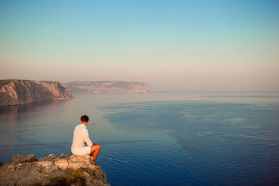 Rear view of man looking at sea against sky