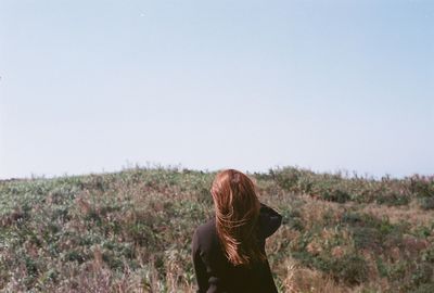 Rear view of woman standing on field against clear sky