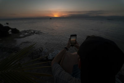 Man photographing sea at sunset