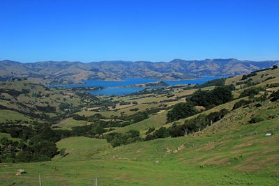 Scenic view of landscape and mountains against clear blue sky