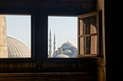 Buildings against sky seen through window