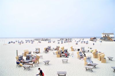 High angle view of people with hooded chairs at beach against sky