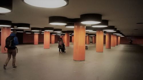 Rear view of woman walking in illuminated corridor