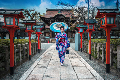 Woman standing on footpath amidst buildings