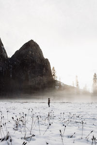 People on snow covered land against sky