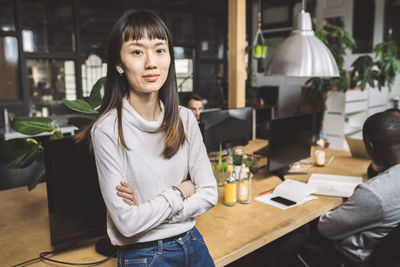 Portrait of confident businesswoman with arms crossed at workplace