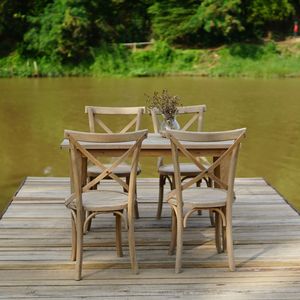 Empty chairs with table arranged on pier over lake