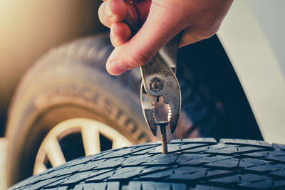 Cropped hand of person removing nail from tire