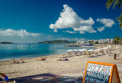 Menu board at beach by sea against sky in sunny day