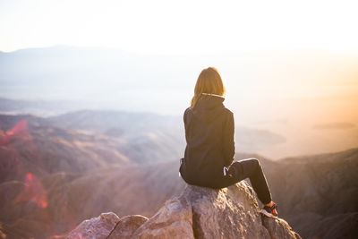 Rear view of man on rock against sky