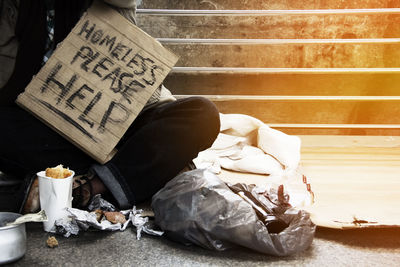 Low section of beggar with placard sitting in tunnel