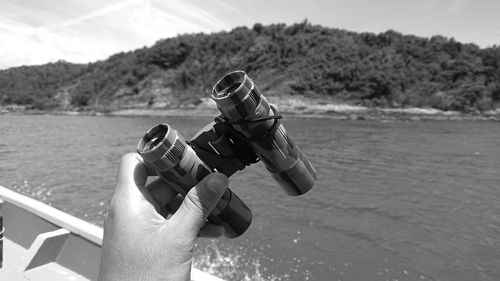 Cropped hand person holding binoculars at sea