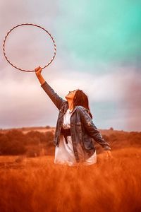 Young woman with hoop while standing on grassy field