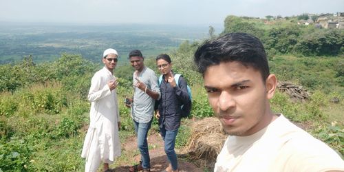 Portrait of friends standing on mountain against plants