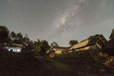 Houses and trees against sky at night