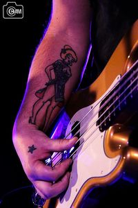 Midsection of man playing guitar against black background