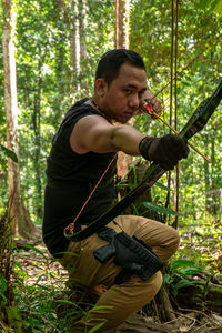 Side view of young man sitting in forest