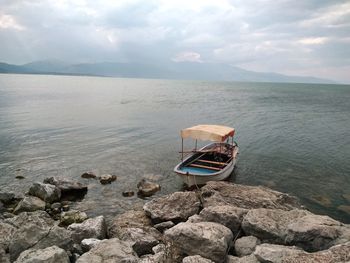 Boat on rock by lake against sky