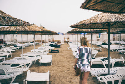 Rear view of woman on beach against sky