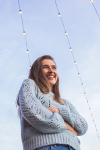 Portrait of smiling young woman standing against sky