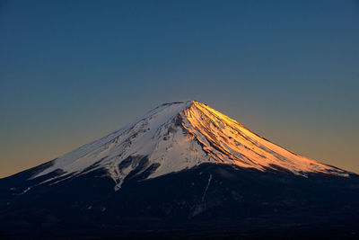 Scenic view of snowcapped mountain against clear sky during winter